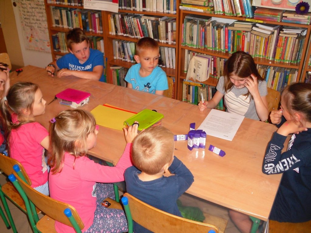 dzieci z uwagą słuchają opowieści czytanej przez jedną z uczestniczek zajęć