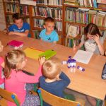 dzieci z uwagą słuchają opowieści czytanej przez jedną z uczestniczek zajęć