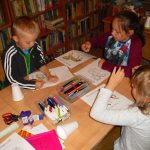 dzieci z zaangażowaniem kolorują swoje karuzelowe koniki