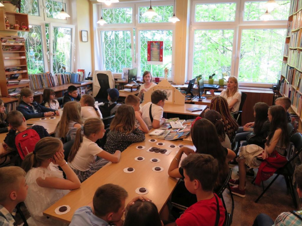 Goście z Ukrainy siedzą w czytelni Biblioteki Głównej i z zainteresowaniem oglądają teatrzyk kamishibai