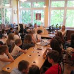 Goście z Ukrainy siedzą w czytelni Biblioteki Głównej i z zainteresowaniem oglądają teatrzyk kamishibai