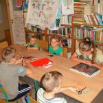dzieci uczestniczące w wakacyjnych zajęciach z uwagą słuchają opowieści o  skarpetce czytanej przez jedną z dziewczynek