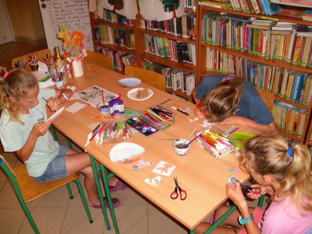 dzieci w skupieniu malują papierowe talerzyki, które będą tłem dla naszych kwitnących roślinek