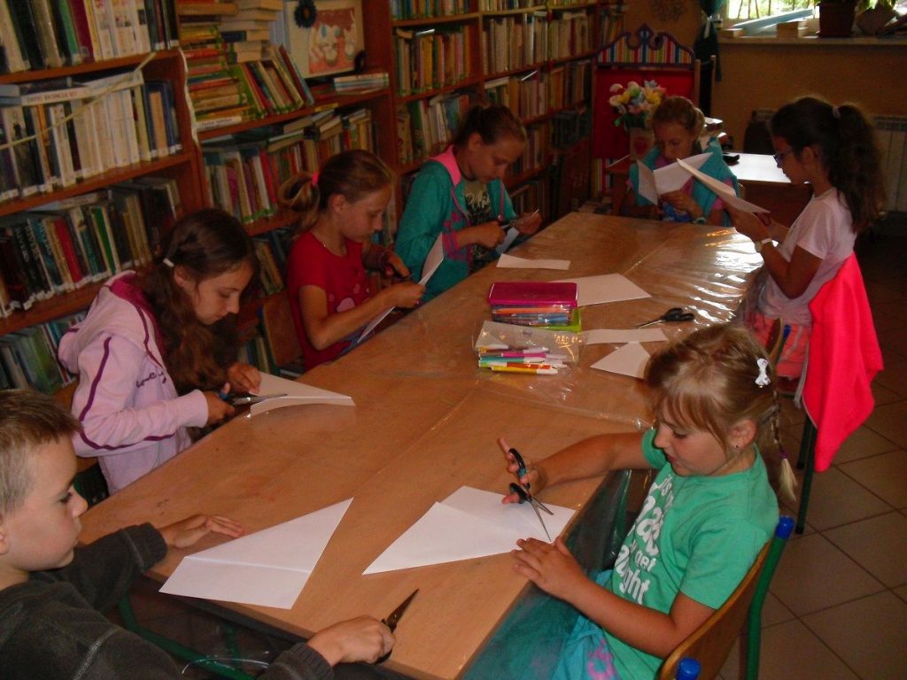 dzieci w skupieniu wycinają i składają kartki do dzisiejszej pracy