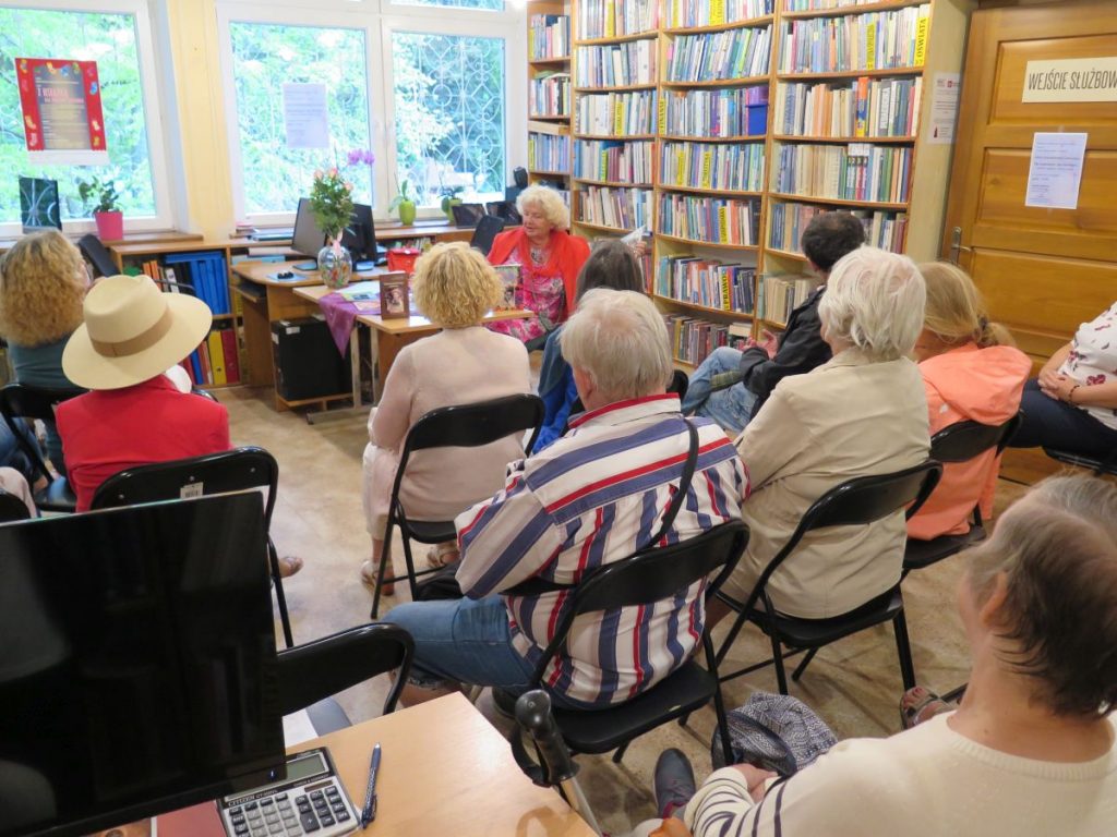 Zgromadzeni czytelnicy z zainteresowaniem przeglądają najnowsze książki pani Felicji