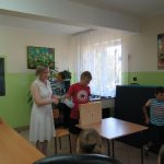 Zgromadzone na świetlicy dzieci siedzą na krzesłach i ochoczo zgłaszają się chcąc odpowiedzieć na pytania Pani Bibliotekarki