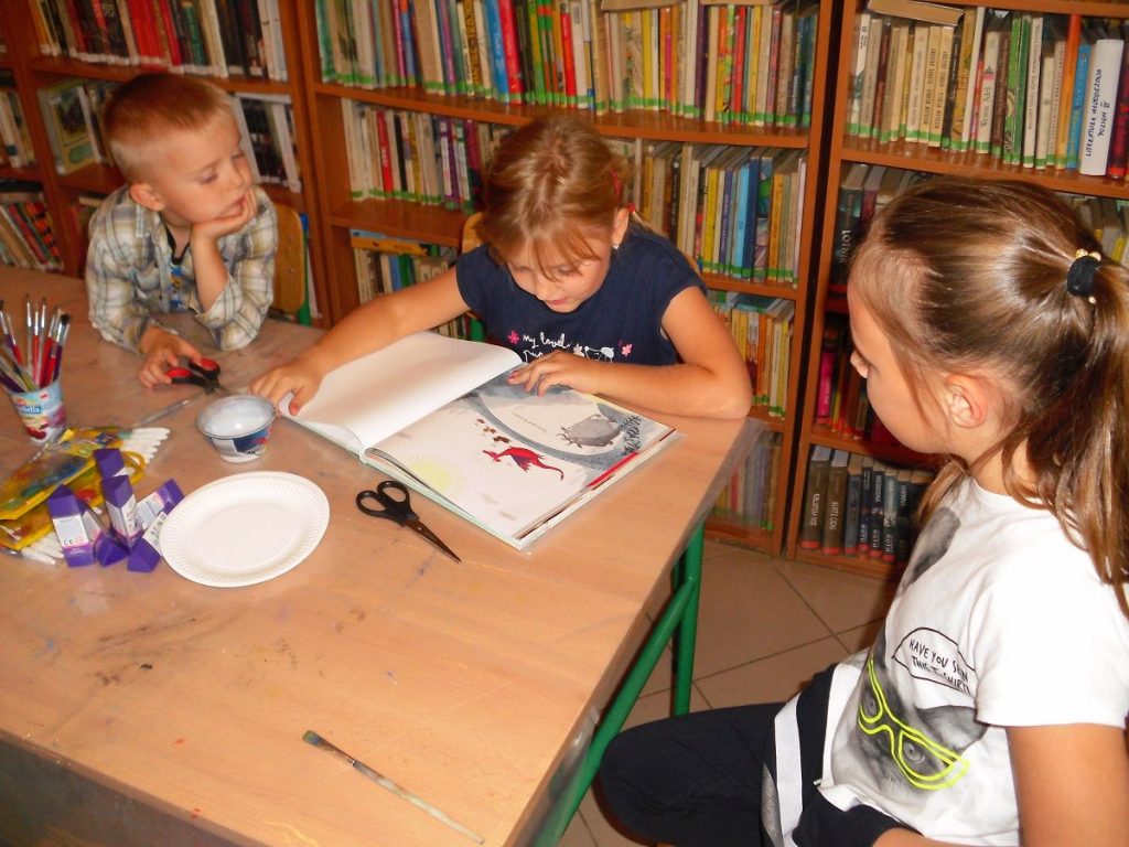 dzieci z uwagą słuchają bajki czytanej przez jedną z dziewczynek
