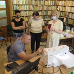 Na zdjęciu mężczyzna tłumaczy zasady działania hafciarki trzem kobietom które pracują w bibliotece