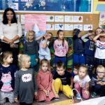 Grupa dzieci stoi z paniami bibliotekarkami oraz z panią wychowawczynią z przedszkola