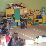 Grupa przedszkolaków słucha czytanej przez bibliotekarza bajki