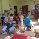 Grupa przedszkolaków bierze udział w zabawie ruchowej pt. "Orzechobranie" polegającej na tym, że przedszkolaki wcielają się w role wiewiórek i gromadzą zapasy na zimę w postaci szyszek, orzechów, kasztanów.