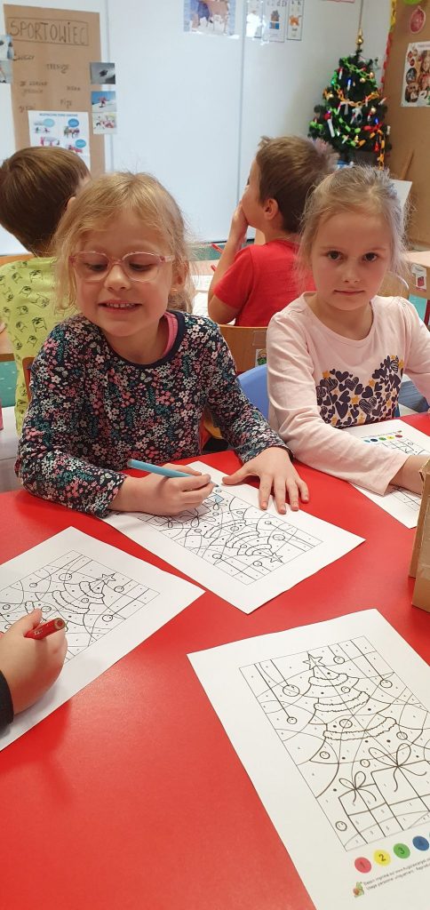 Dwie dziewczynki siedzą przy stoke i wykonuja prace plastyczne