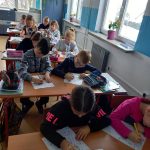 Dzieki z pierwszych klas szkoły podstawowej siedzę w ławkach i wykonują rysunki.