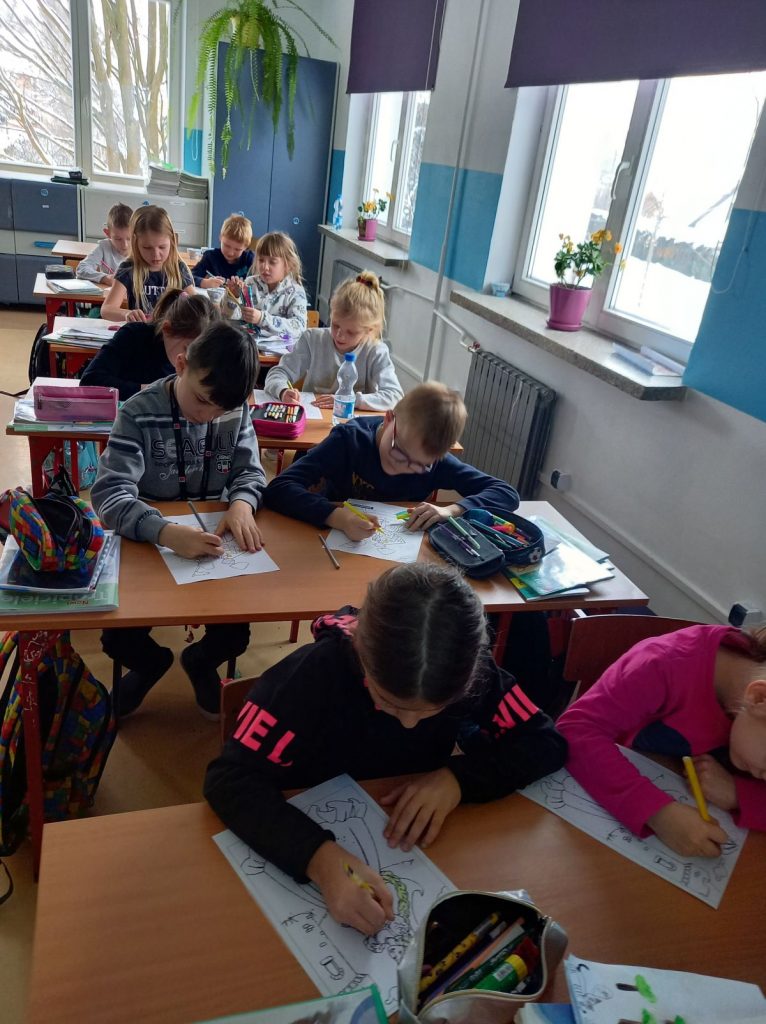 Dzieki z pierwszych klas szkoły podstawowej siedzę w ławkach i wykonują rysunki.