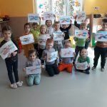 Na środku sali ustawiła się uśmiechnięta grupa przedszkolaków, każde trzyma w rękach narysowaną przed momentem wspaniałą podniebną maszynę
