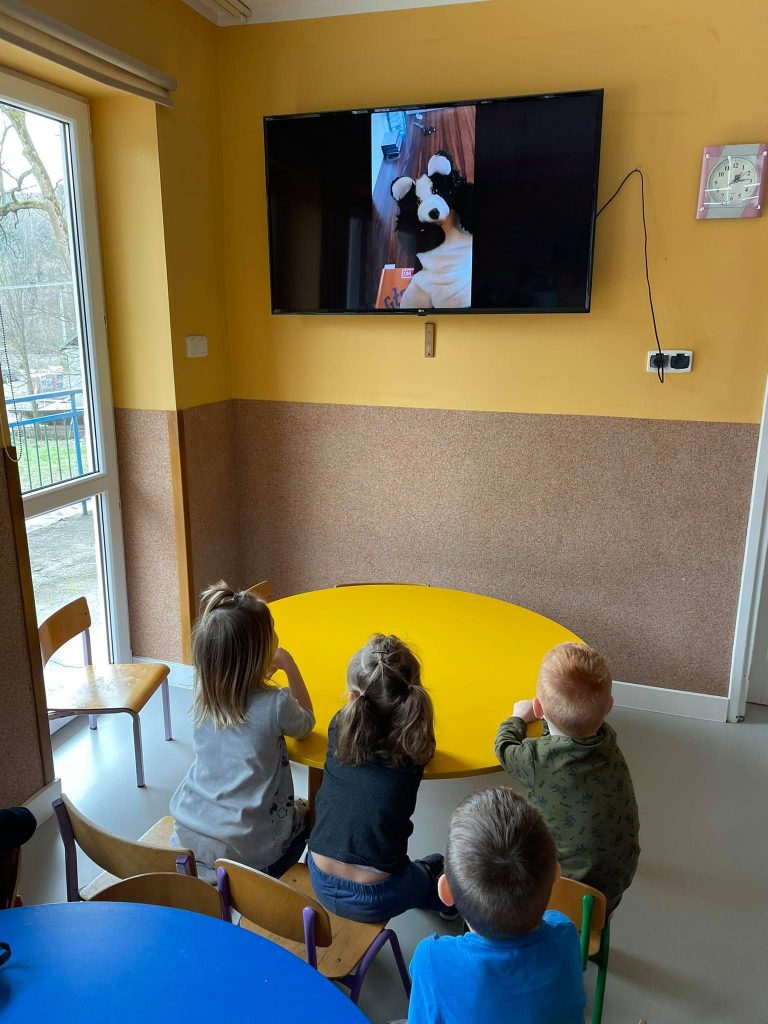 W przedszkolnej sali siedzą dzieci i z zaciekawieniem wpatrują się w duży ekran telewizora na którym widać czytającego bajkę Pana Borsuka