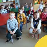 W sali przedszkolnej grupa dzieci siedzi na krzesełkach i słucha bajki pt. „Jak mama została Indianką”.