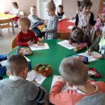 Przy małych stoliczkach siedzą przedszkolaki i z zapałem kolorują na kartkach bukiety kwiatów dla swoich kochanych Mam.