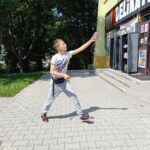Na zdjęciu chłopiec w wieku szkolnym podskakuje z plastikowym kubkiem