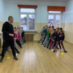 Grupa dzieci stoi podzielona na dwie drużyny w szerokich rozkrokach. Za chwilę zaczną się „wyścigi w tunelach” i zabawa „sałatka jarzynowa”.
