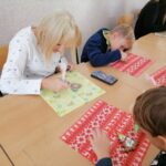 Na zdjęciu widoczna jest kobieta oraz dwoje dzieci podczas dekorowania pierniczków.