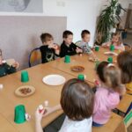 Przy długim stole siedza dzieci i przygotowują się do zajęć