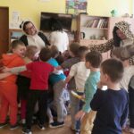Na zdjęciu widać tulące się dzieci a wśród nich przebrane za zwierzaki bibliotekarki