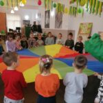 Na zdjęciu widoczna jest grupa przedszkolaków biorących udział w zabawie z chustą animacyjną.