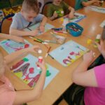 Na zdjęciu widocznych jest sześcioro przedszkolaków wykonujących pracę plastyczną pt. "Kraina dinozaurów" metodą kolażu.