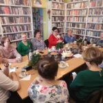 na zdjęciu widać panie siedzące wokół stołu w sali bibliotecznej