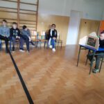 W szkolnej sali gimnastycznej trwa przedstawienie. Zgromadzeni uczniowie oglądają teatrzyk obrazkowy Kamishibai pt. „Jak żyje Ziemia”, który demonstruje im bibliotekarz.