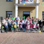 Na zdjęciu widoczna jest grupa ok 81 uczniów z Kl. I – III Szkoły Podstawowej w Tyliczu i Zespołu Szkolno-Przedszkolnego w Muszynce, uczestniczących w imprezie plenerowej zorganizowanej przez Bibliotekę Publiczną, Świetlicę „Przystań” i Centrum Kultury. Dzieci przebrane są w kolorowe stroje m.in. za elfy, krasnale, wróżki wpisując się w motyw przewodni imprezy. Uczniowie pozują do wspólnego zdjęcia przed budynkiem WDK w Tyliczu.