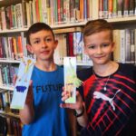 na zdjęciu widać dwóch chłopców,stoja obok siebie, trzymają w rękach wykonaną pracę plastyczną