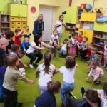 Na zdjęciu widać dzieci wykonujące ćwiczenia, wśród nich bibliotekarkę, przedszkolankę oraz siostrę zakonną.