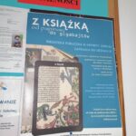 Zdjęcie na którym widać wiszący na szkolnej gazetce plakat informujący o odbywających się dzisiejszego dnia warsztatach „Z książką od papirusu do gigabajtów”.