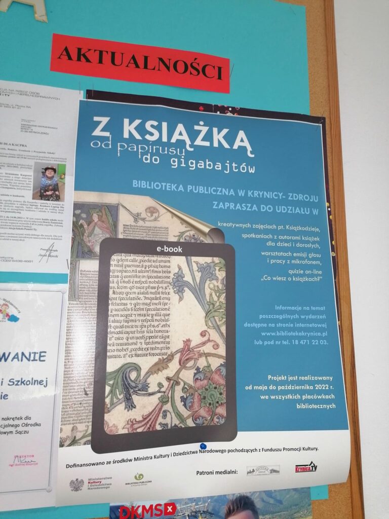 Zdjęcie na którym widać wiszący na szkolnej gazetce plakat informujący o odbywających się dzisiejszego dnia warsztatach „Z książką od papirusu do gigabajtów”.