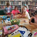 na zdjęciu widać dzieci pracujące przy stole w sali bibliotecznej