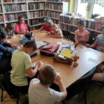 na zdjęciu widać dzieci pracujące przy stole w sali bibliotecznej
