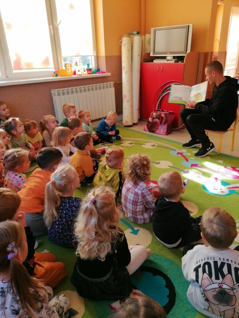 W przedszkolnej sali dzieci siedzą w kółeczku i słuchają z zainteresowaniem bajki o „Misiu Tulisiu”.