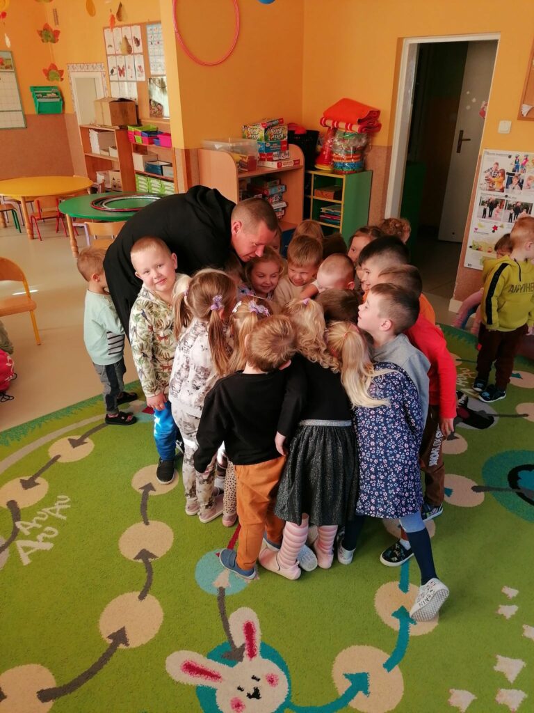 Przedszkolaki zbiły się w ciasną grupkę kładąc swoje ręce na rękę pana bibliotekarza. Za chwilę nastąpi pożegnanie gromkim okrzykiem: „Hej wiewiórki!”.