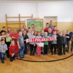 Wszystkie dzieci biorące udział w patriotycznych warsztatach ustawiły się razem z panem bibliotekarzem do pamiątkowego zdjęcia na tle wiszącej za ich plecami mapy.