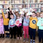 na zdjęciu widać dzieci w wieku przedszkolnym stojące na tle regałów z książkami