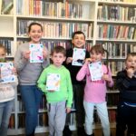na zdjęciu widać dzieci które stoją na tle regałów z książkami