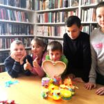 na zdjęciu widać dzieci stojące za stołem na którym ułożono kolorowe słoiki.