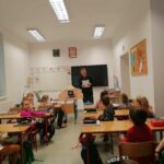 Pan bibliotekarz stoi na środku klasy i czyta słuchającym go z rozbawieniem uczniom zabawne śląskie zwroty i słowa gwarowe.