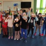 na zdjęciu widać dzieci stojące i trzymające papierowe okulary