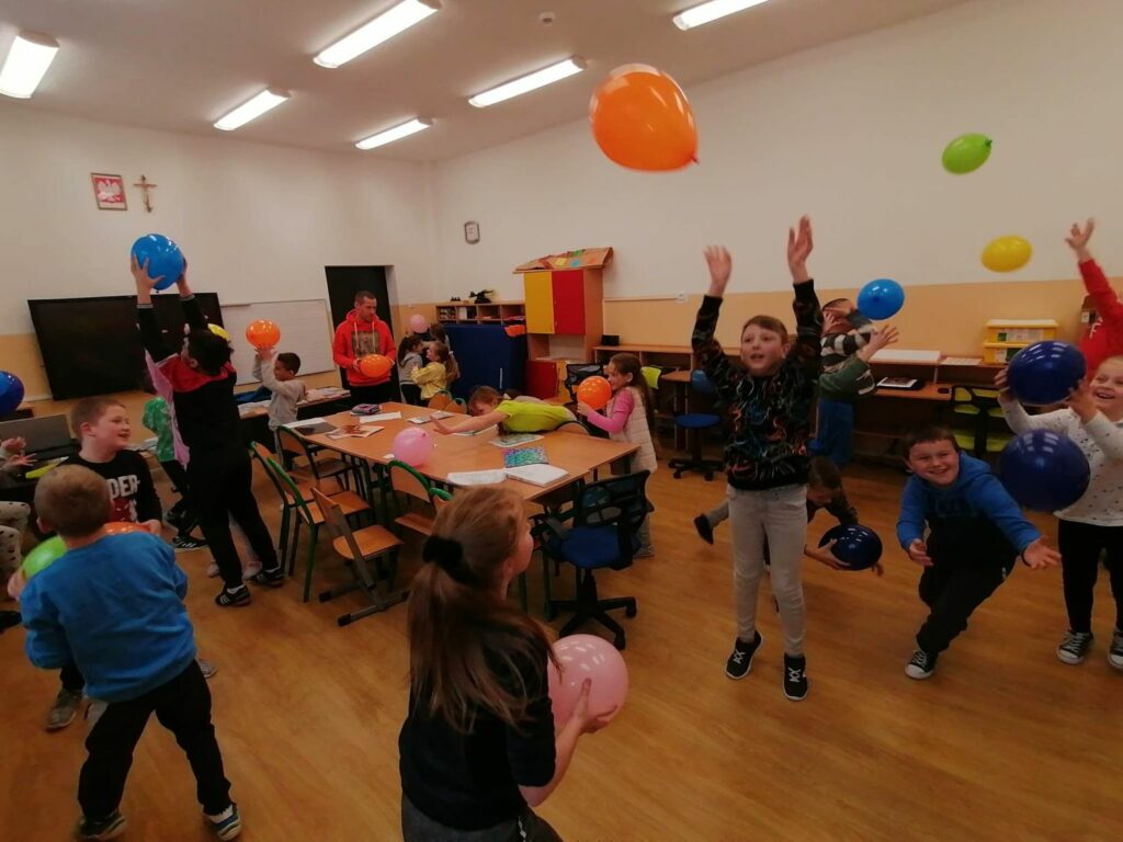 Wszystkie dzieci stoją i z uśmiechami na ustach odbijają do góry kolorowe baloniki.