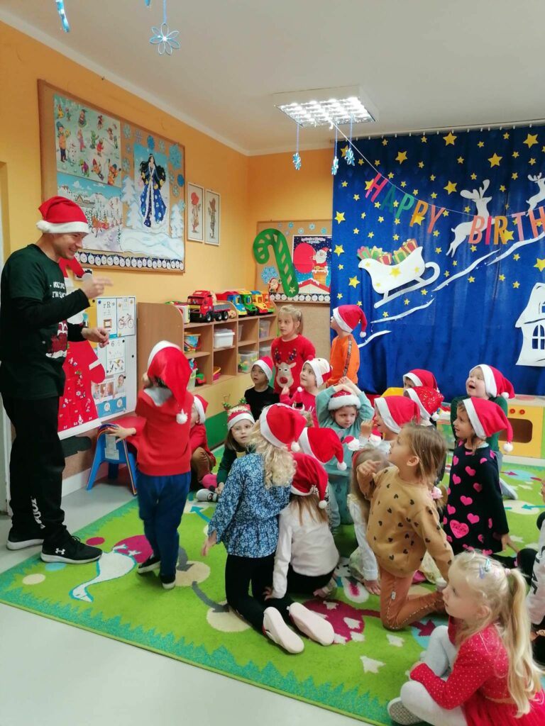 Wszystkie przedszkolaki patrzą z przejęciem i zaciekawieniem na pana bibliotekarza, który stojąc przed nimi naśladuje pewien sport zimowy, a dzieci muszą odgadnąć jaki.