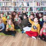 na zdjęciu widać dzieci siedzące na ziemi trzymające papierowe choinki