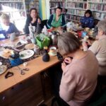 na zdjęciu widać salę biblioteczną oraz stoły wokół których siedzą seniorki